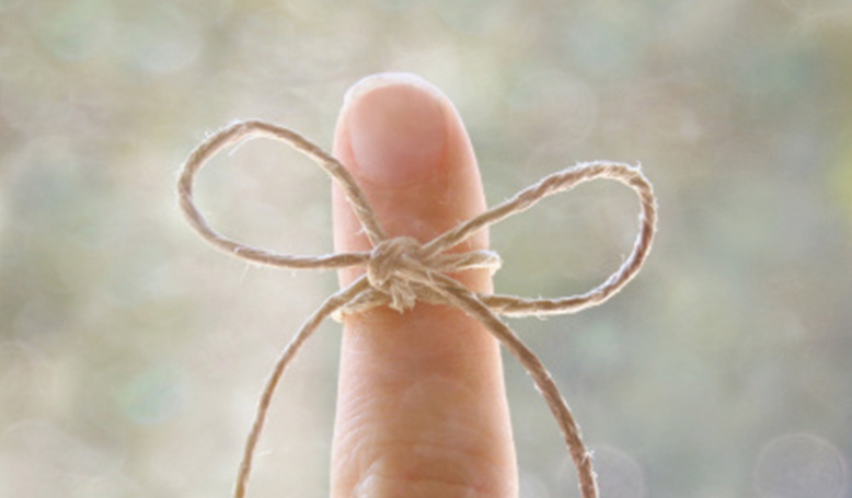 String tied in a bow around a finger; meant to symbolise trying to remember something.